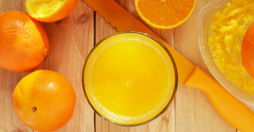 Fresh orange juice and oranges on a wooden kitchen counter in morning light