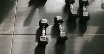 Hexagonal dumbbells resting on a gym floor in natural sunlight