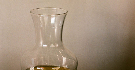 A glass pitcher and a glass of water on a wooden table in soft natural light