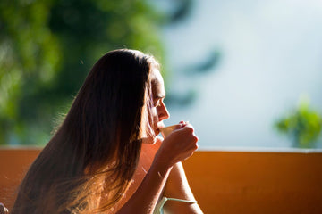 Woman peacefully sipping tea outdoors in morning sunlight