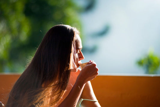 Woman peacefully sipping tea outdoors in morning sunlight