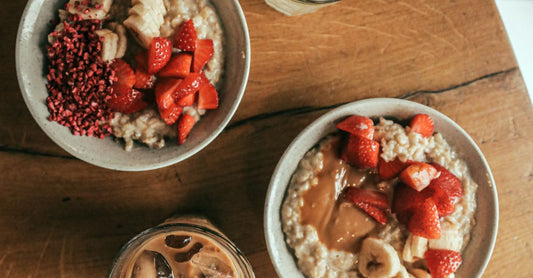 Bowls of oatmeal with fruit on a wooden breakfast table in natural light